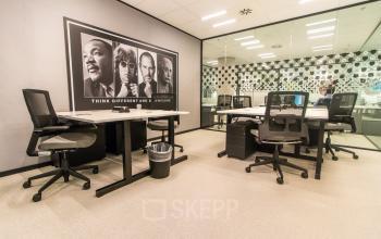 Gemeubileerde kantoorruimte huren op Gustav Mahlerplein in Amsterdam Zuidas, met moderne bureaus en een inspirerende poster aan de muur.