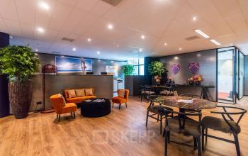 Kantoorruimte huren op Claude Debussylaan 7-29, Amsterdam Zuidas met een gemeubileerde lounge en vergadertafel in een stijlvolle setting.