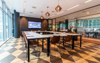 Stijlvolle vergaderruimte in een kantoorpand aan de Claude Debussylaan 7-29, Amsterdam Zuidas, met lange tafels, bruine stoelen en decoratieve lampen, geschikt voor kantoorruimte huren.