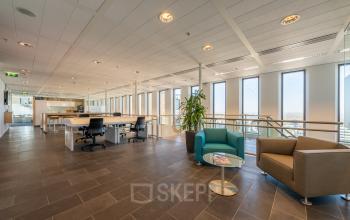 Ruimte in kantoorpand op Gustav Mahlerplein 109-115, Amsterdam Zuidas, voorzien van werkplekken, zitgedeelte en grote ramen.