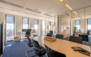 Kantoorruimte huren op Gustav Mahlerplein 109-115 in Amsterdam Zuidas, met bord vergadertafel, stoelen, computers en ramen met prachtig uitzicht over de stad.