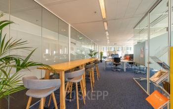 Interieur van een modern kantoorpand op Gustav Mahlerplein 109-115, Amsterdam Zuidas, met glazen wanden, werkplekken, hoge tafels en bureaus, planten voor ontspanning in de kantoorruimte huren.