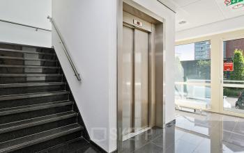 Lichte entree van het kantoorpand aan de Linie 580-596 in Apeldoorn, met trap en lift.