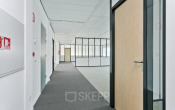 In het kantoorpand op Linie 580-596, Apeldoorn, zie je een ruime gang met verschillende deuren naar kantoor ruimtes.