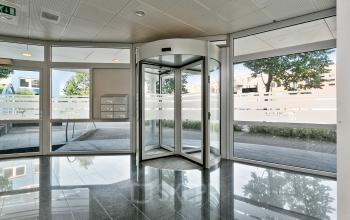 Kantoorruimte huren: Entree van het kantoorpand aan Linie 580-596 in Apeldoorn met een draaideur en grote ramen.