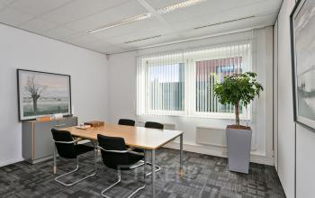 Kantoorruimte te huur met vergadertafel, vier stoelen, plantenbak en kunst aan de muur in kantoorpand op Linie 580-596, Apeldoorn.