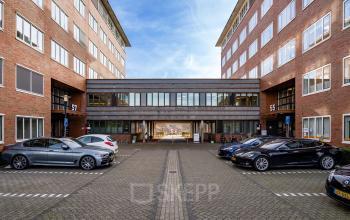 Kantoorpand Het Rietveld 55-59 in Apeldoorn met geparkeerde auto's op het terrein; ideaal voor kantoorruimte huren.