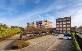 Exterieur van het kantoorpand op Het Rietveld 55-59 in Apeldoorn, omgeven door parkeerruimte en groene begroeiing.