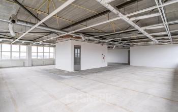 Ongemeubileerde kantoorruimte te huur in Apeldoorn met industriële plafonds en grote ramen voor veel natuurlijk licht.