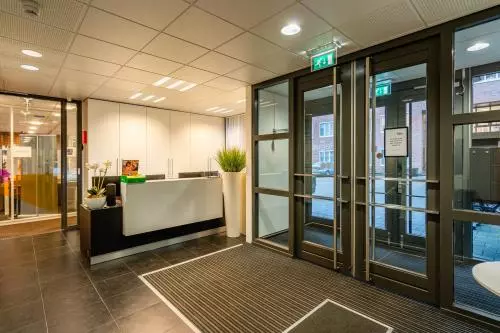 Kantoorpand op Het Rietveld 55-59, Apeldoorn, met een moderne entree en receptieruimte. De glazen deuren bieden toegang tot de kantoorruimte. Ideaal voor wie een kantoor wil huren.