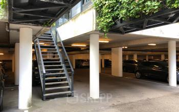 Parkeergarage onder kantoorpand op Wapenrustlaan 11-31, Apeldoorn. Verschillende auto's geparkeerd onder betonnen constructie met trap naar bovengelegen etages. Ideaal voor werknemers die kantoorruimte willen huren met handige parkeerfaciliteit.