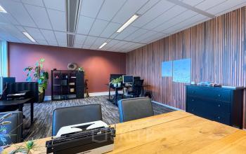 Moderne kantoorruimte huren in Apeldoorn aan Wapenrustlaan 11-31. De ruimte is ingericht met werkplekken, planten en hedendaagse meubels, ideaal voor een productieve werkomgeving.