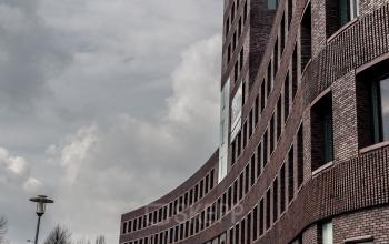 Moderne architectuur van het kantoorpand aan Wapenrustlaan 11-31 in Apeldoorn, met geparkeerde auto's voor de deur.