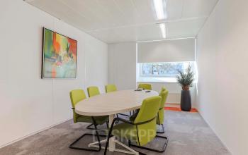 Kantoorruimte huren aan de Prins Willem-Alexanderlaan 301 in Apeldoorn, met een vergadertafel en zes groene stoelen onder helder licht.