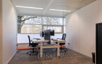 Moderne en lichte kantoorruimte te huur op Prins Willem-Alexanderlaan 301 in Apeldoorn met twee werkplekken en grote ramen voor natuurlijk licht.
