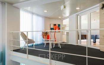 Lichte en moderne kantoorruimte op de bovenverdieping met glazen deuren en minimalistische inrichting in Apeldoorn.