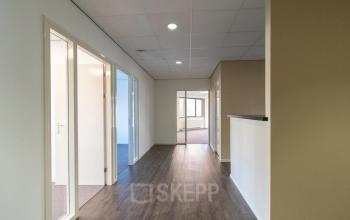 Heldere kantoorgang met houten vloer en vier deuren naar kantoorruimtes op Prins Willem-Alexanderlaan 401, Apeldoorn.