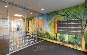 Entree van kantoorpand op Prins Willem-Alexanderlaan 401, Apeldoorn, met glazen deuren en boslandschapfotobehang op de muren. Ideaal voor kantoorruimte huren.