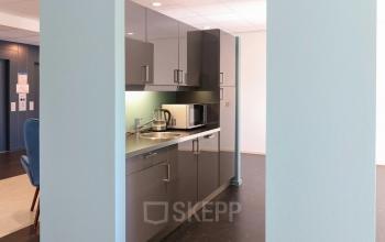 Kantoorruimte huren in Apeldoorn met een moderne, compacte pantry met grijze kasten, een magnetron, en een koffiezetapparaat, gelegen in het kantoorpand aan de Prins Willem-Alexanderlaan 401.
