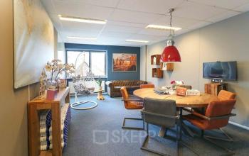 Gezellig ingerichte kantoorruimte te huur in Apeldoorn, met zithoek en vergadertafel, aan de Prins Willem-Alexanderlaan 401.