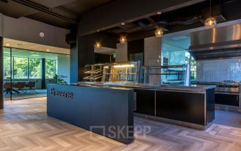 Moderne kantoorruimte te huur op Landdrostlaan 51, Apeldoorn, met een stijlvolle brasserie en uitzicht op het groene buitengebied.