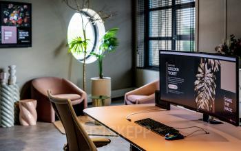 Moderne kantoorwerkplek met stijlvol interieur op Lange Amerikaweg, Apeldoorn, met comfortabele zitstoelen, grote monitor en planten. Perfect voor wie wil kantoorruimte huren in een inspirerende omgeving.