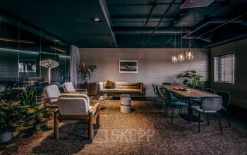 Modern ingerichte kantoorruimte in Apeldoorn met zitgedeelte en vergadertafel aan Lange Amerikaweg 55-61.