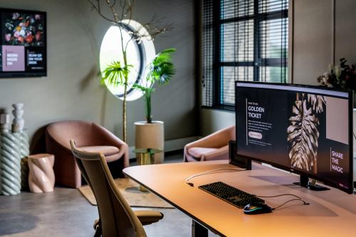 Moderne kantoorwerkplek met stijlvol interieur op Lange Amerikaweg, Apeldoorn, met comfortabele zitstoelen, grote monitor en planten. Perfect voor wie wil kantoorruimte huren in een inspirerende omgeving.