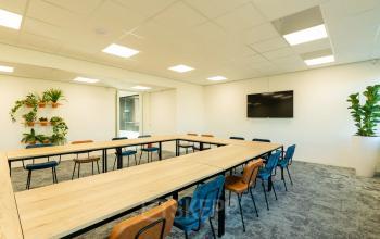 Kantoorruimte in Apeldoorn aan de Prins Willem Alexanderlaan 701 met een moderne inrichting, bestaande uit een grote tafel, stoelen en planten. Beschikbaar voor gebruik als vergaderruimte.