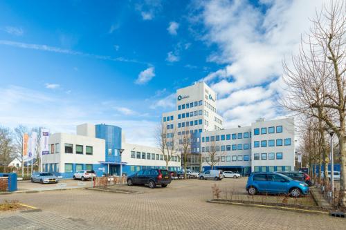 Exterieur van het kantoorpand op Prins Willem Alexanderlaan 701, Apeldoorn, met parkeerplaatsen aan de voorzijde en een blauwe lucht. Perfect voor kantoorruimte huren.