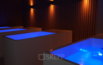 Moderne ontspanningsruimte in kantoorpand op Schumanpark 9, Apeldoorn, met sfeerverlichting en glanzend water in ligbaden.