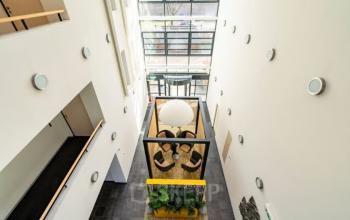 Lichte entree van een kantoorpand aan Schumanpark 9 in Apeldoorn, met moderne glazen scheidingswanden en een centrale zithoek. Geschikt voor kantoorruimte huren.