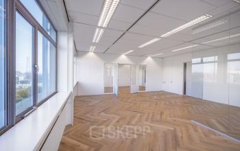 Lichte kantoorruimte met grote ramen en houten vloer in Apeldoorn, ideaal voor wie op zoek is om kantoorruimte te huren op Oude Apeldoornseweg 41-45.