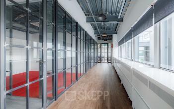 Heldere kantoorruimte huren aan de Oude Apeldoornseweg 41-45, met stijlvolle glazen wanden en houten vloer in Apeldoorn. Ideaal kantoorpand voor moderne werkplekken.