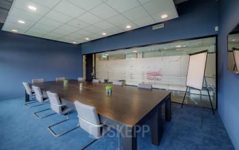 Vergaderruimte in Apeldoorn op de Oude Apeldoornseweg 41-45 met moderne meubels en glazen wand. Onderdeel van het kantoorpand, ideaal voor wie kantoorruimte wil huren.