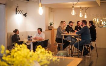 Gezellige kantine in het kantoorpand aan Roggestraat 111, Apeldoorn, met mensen die samen lunchen en praten aan tafels.