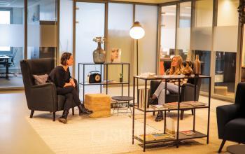 Kantoor op Roggestraat 111 in Apeldoorn met twee mensen zittend in een loungegedeelte in gesprek voor het huren van kantoorruimte.