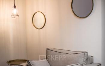 Gezellige wachtruimte in het kantoorpand op Roggestraat 111, Apeldoorn. Ronde spiegels aan de muur en comfortabele stoelen.