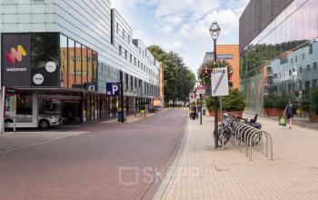 Kantoorpand op Roggestraat 111 in Apeldoorn met moderne gevels en fietsenrekken aan de voorkant. Twee personen lopen langs de straat.