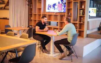 Kantoorruimte huren in Apeldoorn, Roggestraat 111, met moderne inrichting en twee mannen in gesprek aan een tafel.