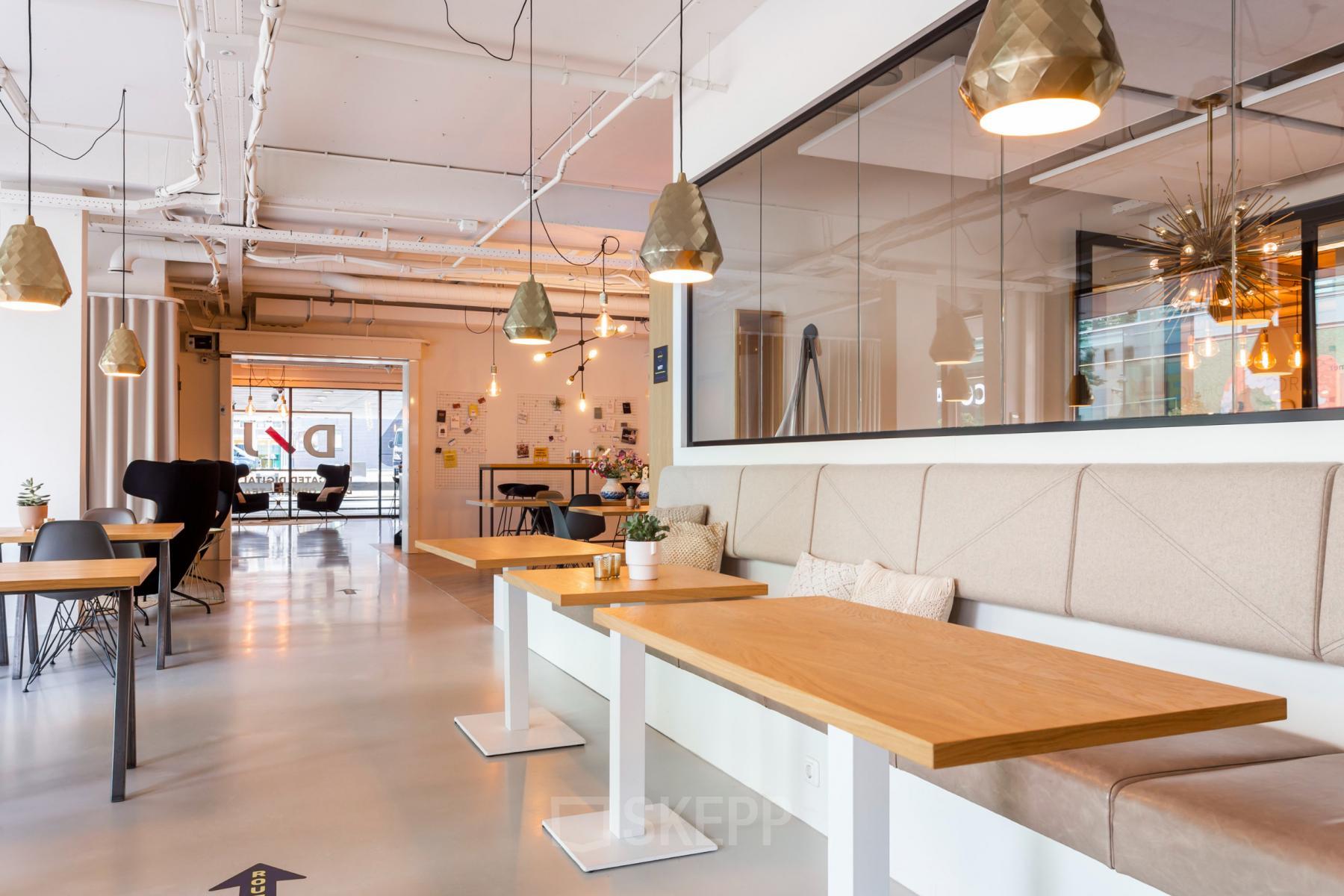 Moderne kantooruimte huren op Roggestraat 111 in Apeldoorn met houten tafels, comfortabele banken en stijlvolle verlichting.