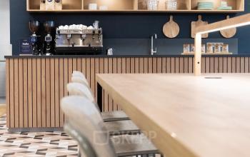 Moderne koffiecorner in kantoorpand aan Jansbuitensingel 30, Arnhem Centrum, met sfeervolle decoratie en barstoelen.