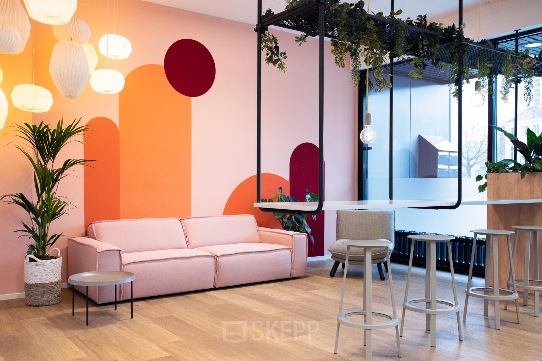 Moderne kantoorlounge in Arnhem Centrum aan de Jansbuitensingel 30, voorzien van een comfortabele roze bank, stijlvolle sta-tafels en speelse kleuraccenten.