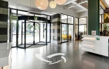 Ingang van het kantoorpand aan de Jansbuitensingel 7 in Arnhem Centrum, met moderne glazen deuren en minimalistisch interieur. Kantoorruimte huren hier biedt direct toegang tot een dynamische zakelijke omgeving.