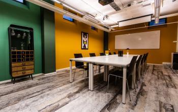 Vergaderruimte in bedrijfsverzamelgebouw aan Jansbuitensingel 7, Arnhem Centrum, met lange tafel, stoelen en speelse groene en gele muurtinten.