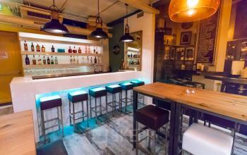 Gezellige kantoorruimte huren aan Jansbuitensingel 7 in Arnhem Centrum, met een moderne baropstelling en hoge tafels, ideaal voor informele vergaderingen of werkpauzes.