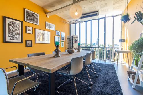 Moderne kantoorruimte met grote ramen en een lange tafel omringd door stoelen in het kantoorpand aan Jansbuitensingel 7, Arnhem Centrum. Ideaal voor vergaderingen of als werkplek.