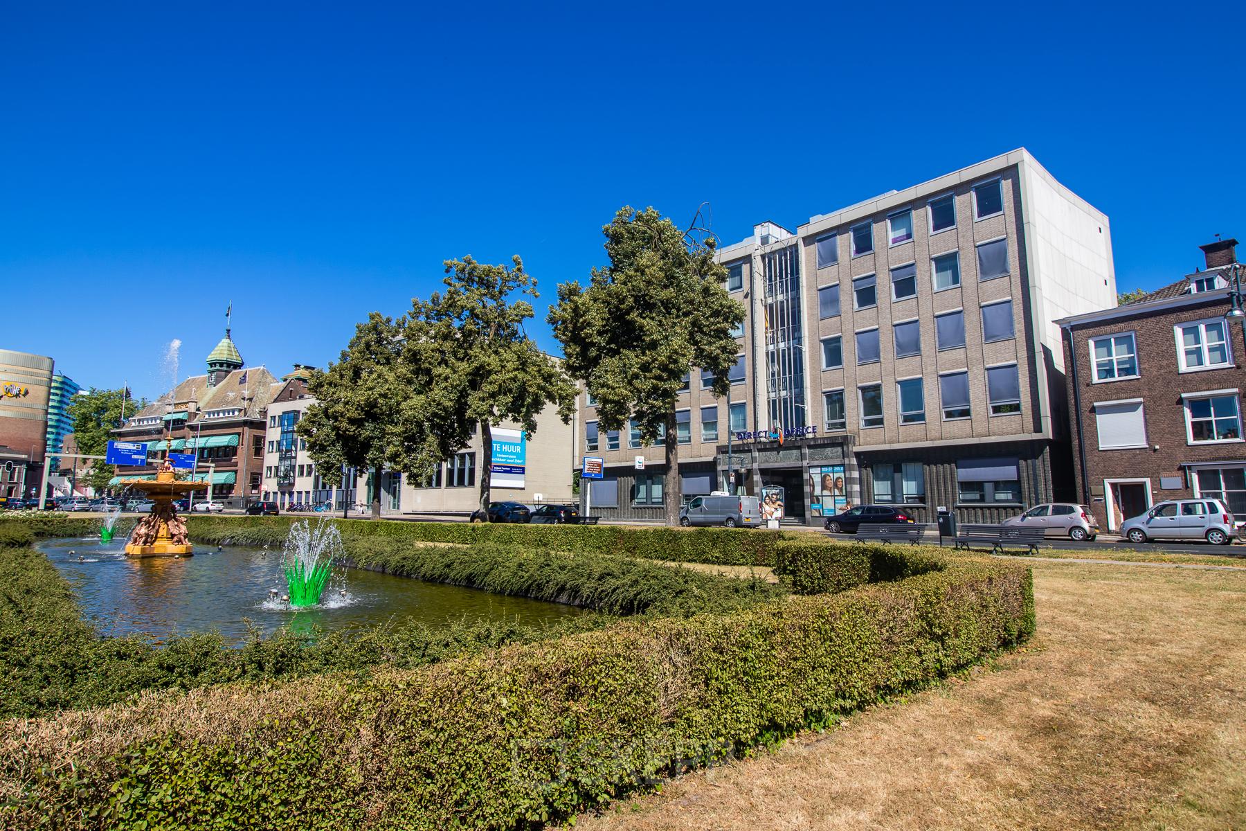 Buitenkant van een kantoorpand op Jansbuitensingel 7, Arnhem Centrum, gezien vanaf een tuin met fontein, geschikt voor kantoorruimte huren.
