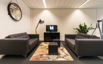 Modern ingerichte kantoorruimte met comfortabele zitbanken en een stijlvolle staande lamp, gelegen op Meander 251, Arnhem IJsseloord.