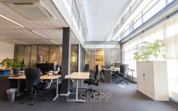 Modern ingerichte kantoorruimte in Arnhem IJsseloord op Meander 251 met glazen scheidingswanden en werkende personen.